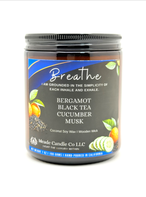 Candle jar with 'Breathe' label featuring bergamot, black tea, cucumber, and musk scents.